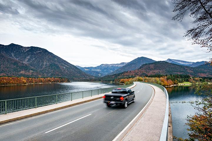 Truck driving on a road topped bridge towards mountains in the distance