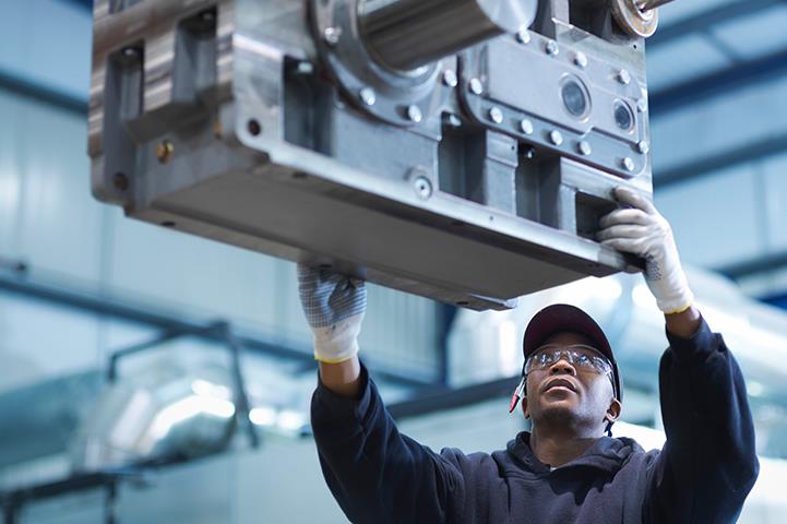 person using crane to move industrial gear box in engineering factory