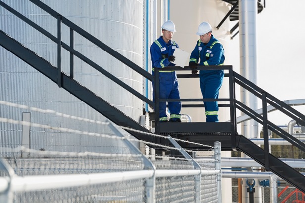two worker talking outside on a platform at a gas plant